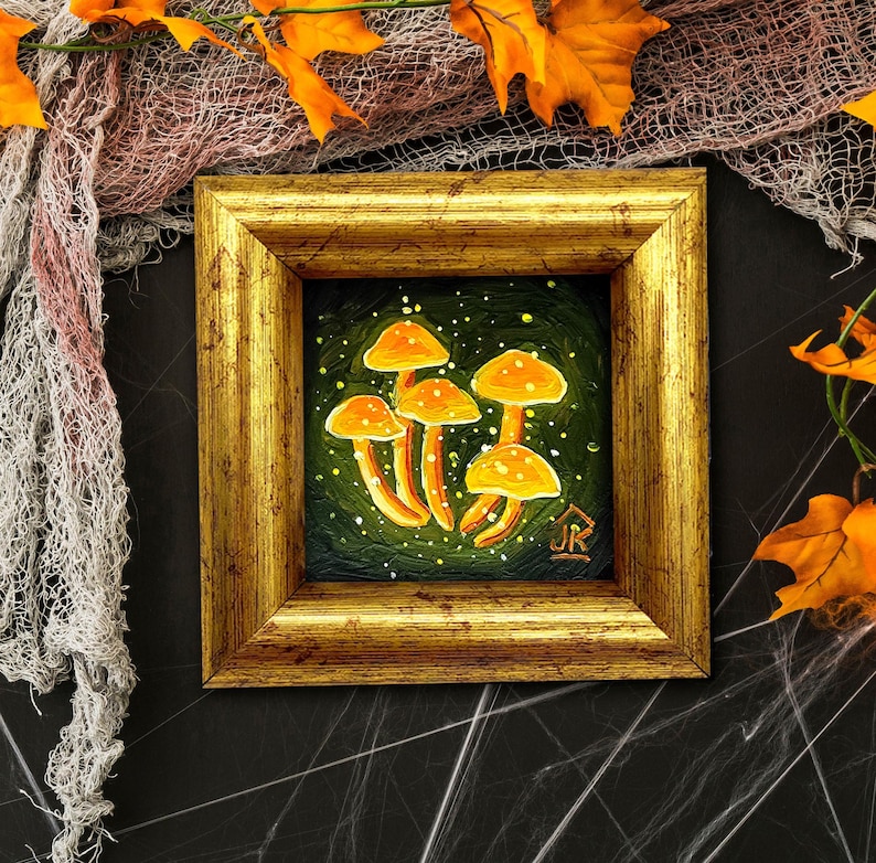 May include: A framed painting of orange mushrooms on a green background with white speckles. The frame is gold with a raised edge.