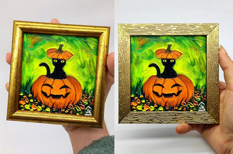 Op de afbeelding: Een vierkant olieverfschilderij in een gouden lijst met een zwarte kat die in een uitgesneden oranje pompoen zit. De kat draagt een klein pompoenplakje als hoed. De achtergrond is levendig groen met zichtbare penseelstreken. De initialen JK staan in de hoek.