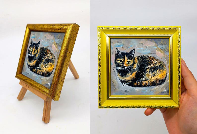 Pode incluir: Uma pequena pintura quadrada de um gato tartaruga com pelo preto, laranja e branco, feita com pinceladas vis&iacute;veis. A obra est&aacute; emoldurada numa moldura amarela brilhante e ornamentada com uma borda texturizada sobre um cavalete de madeira.
