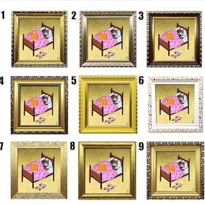 Puede incluir: Nueve pinturas enmarcadas de un gato durmiendo en una cama. Cada pintura tiene un marco de color diferente: dorado, marr&oacute;n, blanco, amarillo y negro. El gato est&aacute; representado en una cama rosa con una manta a cuadros. Las pinturas est&aacute;n numeradas del 1 al 9.