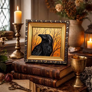 Pode incluir: Uma obra de arte emoldurada com um corvo preto contra um fundo de &aacute;rvores nuas e um c&eacute;u laranja. A moldura &eacute; dourada com uma borda marrom escura. A obra de arte repousa sobre uma pilha de livros antigos.