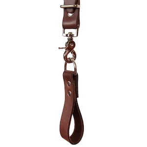 May include: A brown leather camera strap with a metal hook and a loop handle.