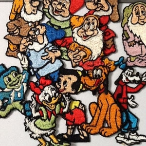 Op de afbeelding: Een verzameling geborduurde strijk-op patches met verschillende Disney-figuren, waaronder Mickey Mouse, Donald Duck, Goofy en de Zeven Dwergen. De patches zijn kleurrijk en gedetailleerd, met een verscheidenheid aan uitdrukkingen en poses.