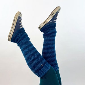 Puede incluir: Un par de polainas rayadas azules con un par de zapatillas Converse azules. Las polainas se llevan sobre unos leggings verde oscuro.