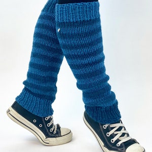 Puede incluir: Un par de polainas de punto azul con un patr&oacute;n de rayas. Las polainas se llevan sobre unos leggings negros y unas zapatillas negras.