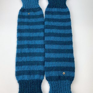 Puede incluir: Un par de polainas de punto a rayas azules y verde azulado con un peque&ntilde;o bot&oacute;n dorado en cada una.