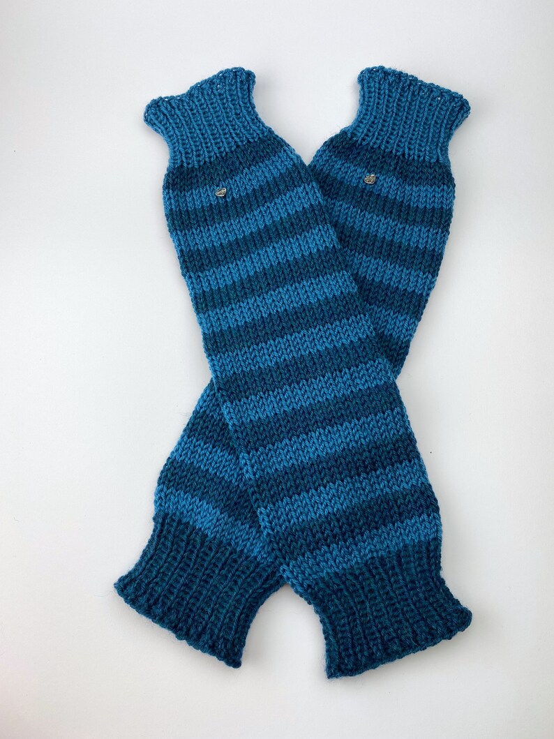 Puede incluir: Un par de polainas de punto a rayas azules y verde azulado. Las polainas est&aacute;n dobladas por la mitad y tienen un peque&ntilde;o bot&oacute;n plateado en cada una.