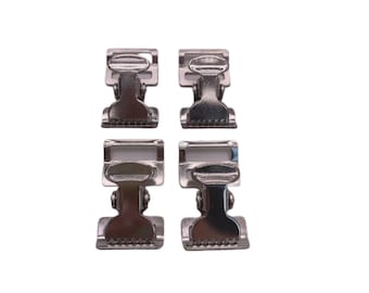 May include: Four silver metal clasps with a spring-loaded mechanism. The clasps are designed to attach to fabric or other materials.