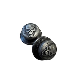 May include: Two silver skull-shaped buttons. The buttons are round and have a raised skull design.