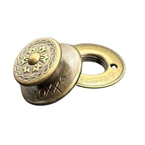 May include: Antique brass-colored LOXX fastener set. The set includes a decorative button with a floral design and a matching washer. The button is marked with the text "LOXX" and the washer has the text "Made in Germany".