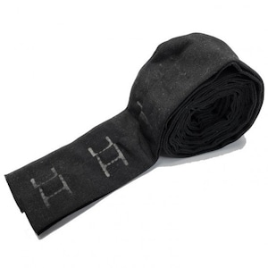 Może przedstawiać: Czarny tubus z tkaniny z powtarzającymi się literami "HH" na całej długości. Tubus jest zwinięty i związany czarną wstążką.