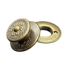 May include: Antique brass-colored LOXX fastener set. The fastener features an oval-shaped head with a floral design and a circular base. The base is stamped with the text "German".