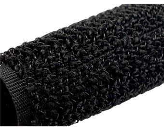 May include: Close-up of a black, textured fabric. The material has a looped, woven appearance, creating a dense, three-dimensional surface. The texture is consistent across the visible area, with a dark, matte finish. The fabric appears to be tightly woven.