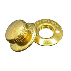 May include: Close-up of three brass-coloured metal fasteners. Two are round with a flat top and the word "LOXX" is visible. The third is a ring with the words "Made in Germany" around the edge. These fasteners are likely used for securing items.