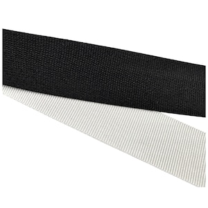 May include: Close-up of two fabric straps. The top strap is black, with a tightly woven texture. The bottom strap is light gray with a striped pattern. Both straps are angled across the frame against a white background.