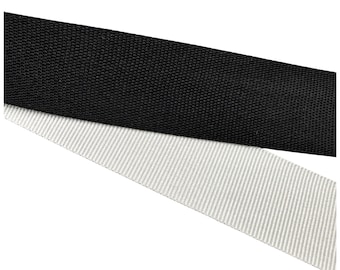 May include: Close-up of two fabric straps. The top strap is black, with a tightly woven texture. The bottom strap is light gray with a striped pattern. Both straps are angled across the frame against a white background.