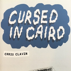May include: A book cover with a blue cloud shape with the text "CURSED IN CAIRO" in white. The author's name, "CHRIS CLAVIN", is printed in black below the cloud. The cover also features a black and white illustration of a building with a sign that reads "ACE OF CUPS".