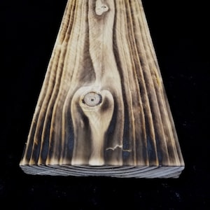 Könnte beinhalten: Nahaufnahme einer verwitterten Holzplanke mit einem Farbspiel aus Dunkelbraun und Hellbraun. Das Holz hat eine natürliche Maserung und einen Knoten in der Mitte.