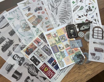 May include: A collection of translucent decorative sticker sheets featuring various printed designs including botanical illustrations, vintage travel stamps, license plates, historical portraits, celestial bodies, and architectural elements.