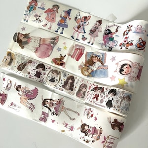 May include: Several rolls of decorative washi tape featuring whimsical illustrations of girls, animals, and fantasy elements. The tape designs include characters in various outfits, stars, and other decorative motifs. The color palette includes pink, purple, and blue.