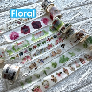 May include: Several rolls of washi tape with floral and botanical patterns. Designs include roses, buildings, and foliage. The word "Floral" is displayed in a blue box. The tape is ideal for crafts.