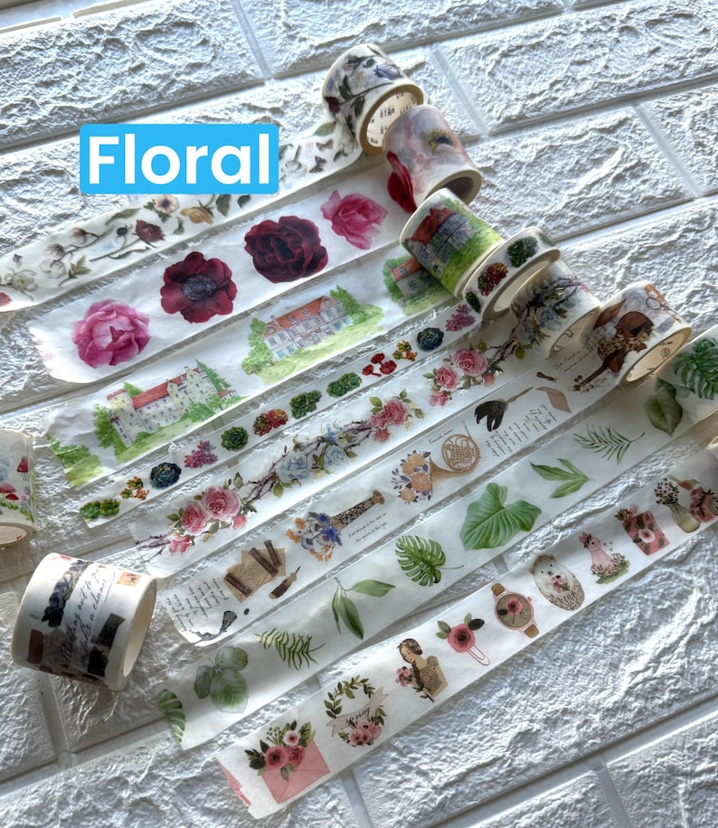 May include: Several rolls of washi tape with floral and botanical patterns. Designs include roses, buildings, and foliage. The word "Floral" is displayed in a blue box. The tape is ideal for crafts.