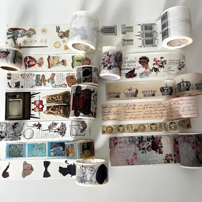 May include: A collection of decorative washi tape rolls with various vintage-inspired designs. The tapes feature images of butterflies, crowns, postage stamps, and architectural elements. The color palette includes shades of cream, black, and floral accents.
