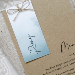 Menú de boda y etiqueta con el nombre de los invitados, tarjetas para el menú de la cena, tarjeta para el lugar de la boda, menú con clip dorado, tarjeta con el nombre de la boda, colección "Kraft y azul océano"