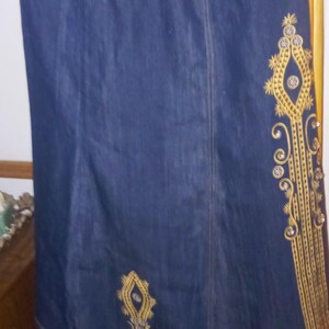 May include: A dark blue denim skirt with gold embroidery. The embroidery features a diamond shape with a floral design and rhinestones.