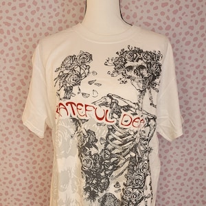 May include: White t-shirt with a black and white graphic print of a skull with roses and the text "Grateful Dead".