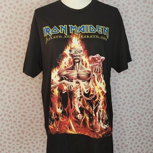 May include: Black t-shirt with a graphic of a skeletal figure in flames holding a skull. The text "Iron Maiden Seventh Son of a Seventh Son" is printed on the shirt.