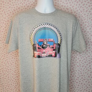 May include: A grey t-shirt featuring a graphic of a red racing car speeding through a checkered flag tunnel. The car has the number 8 on its side and the text "Power 2" is printed beneath the graphic.