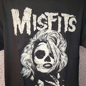 May include: Black t-shirt with a white graphic of a skull with long hair and the word "Misfits" above it.