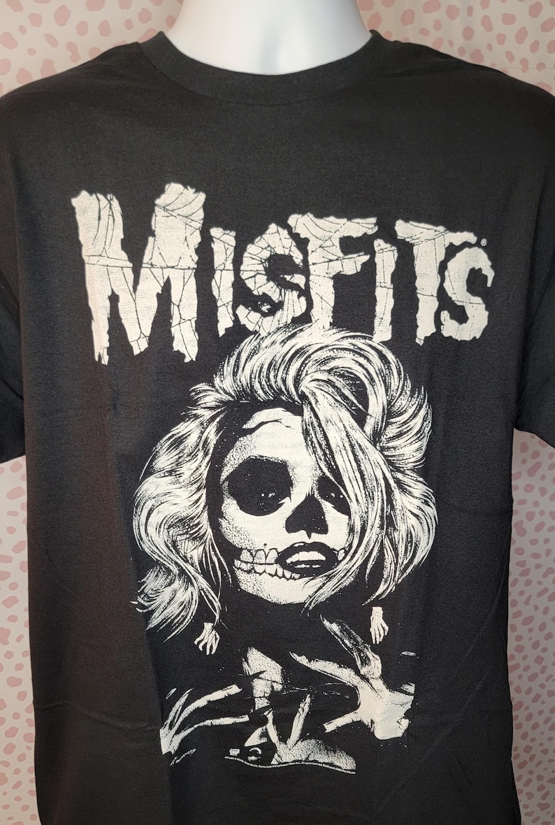 May include: Black t-shirt with a white graphic of a skull with long hair and the word "Misfits" above it.
