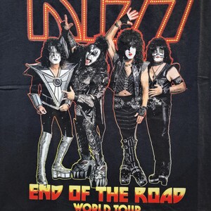 May include: Black t-shirt featuring a red neon KISS logo and the text "End of the Road World Tour". Four band members are pictured in black clothing with makeup.