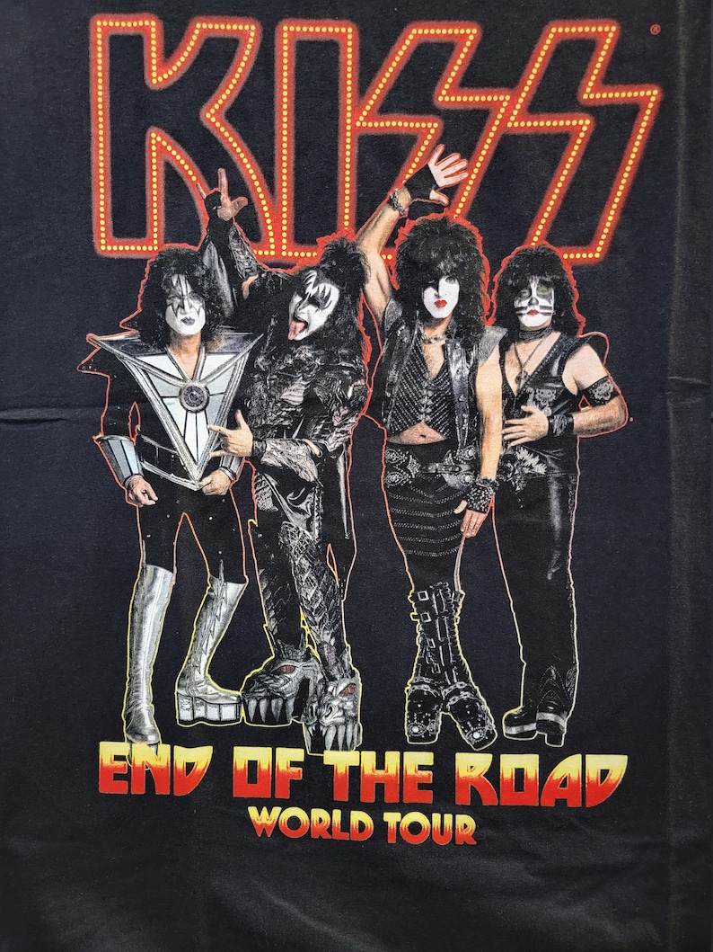 May include: Black t-shirt featuring a red neon KISS logo and the text "End of the Road World Tour". Four band members are pictured in black clothing with makeup.