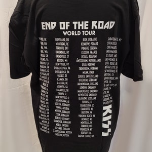 May include: Black t-shirt with white text listing the cities on the "End of the Road World Tour" for the band KISS. The tour dates include cities in North America, Europe, and Russia.