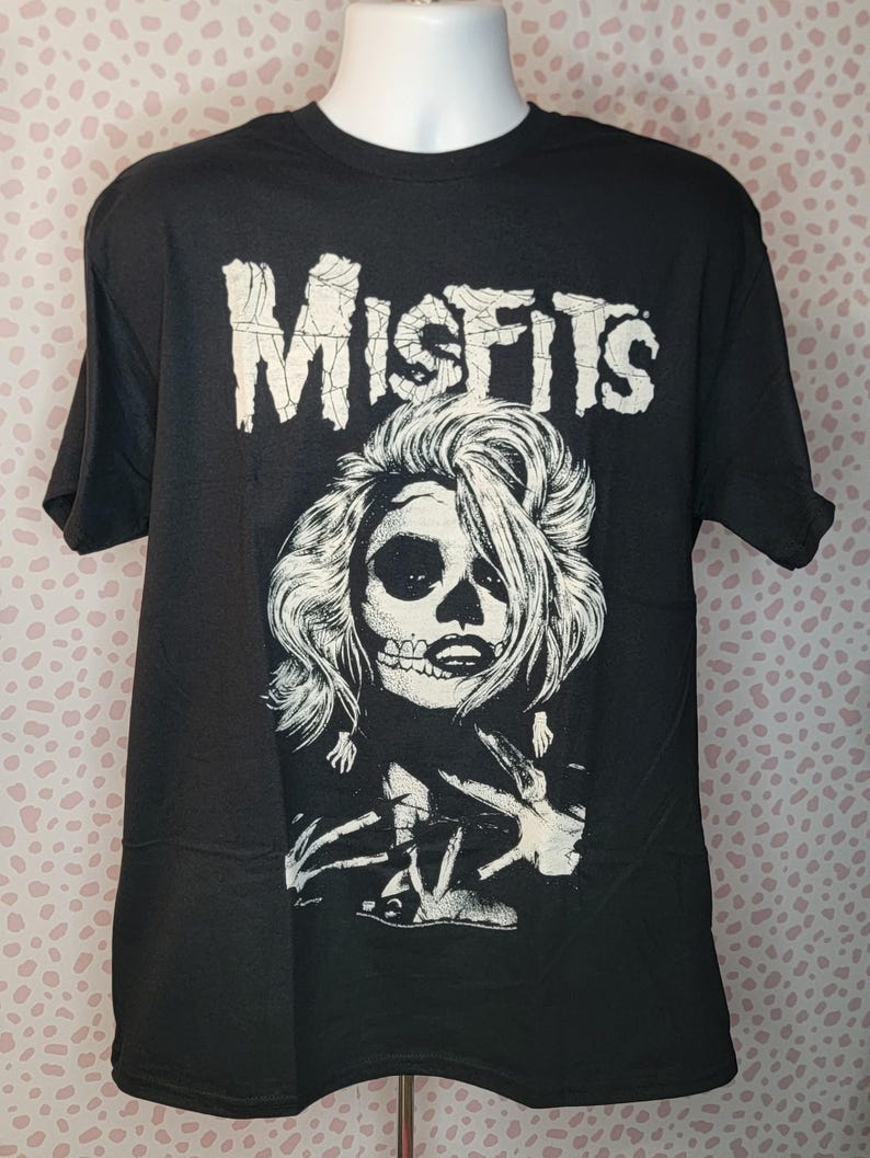 May include: Black t-shirt with a white graphic of a woman with a skull face and the word "MISFITS" above her.