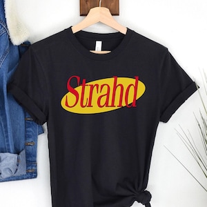 May include: Black t-shirt with a yellow oval graphic that says "Strahd" in red letters.