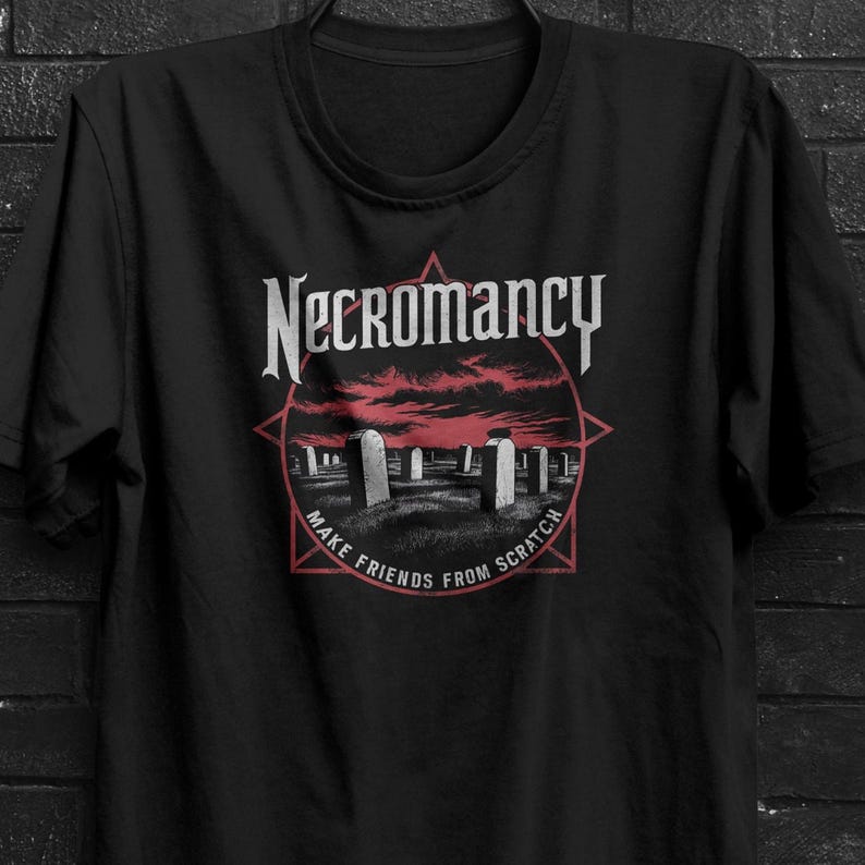 Pode incluir: Camiseta preta com um gr&aacute;fico de um cemit&eacute;rio ao p&ocirc;r do sol e o texto "Necromancy Make Friends From Scratch".