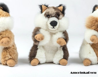 Op de afbeelding: Drie pluche knuffels in de vorm van vossen. De vos links is bruin en wit, de middelste vos is grijs en wit, en de vos rechts is wit met bruine accenten.