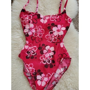 May include: A red swimsuit with a pink floral print. The swimsuit has thin straps and a scoop neck.