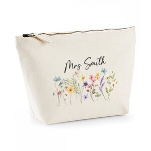 May include: A white canvas zippered pouch with a floral design and the text "Mrs. Smith" printed on it.
