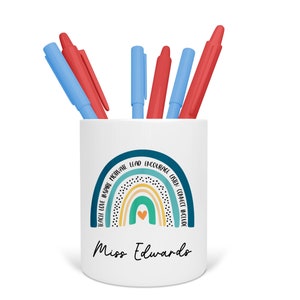 May include: White ceramic pencil holder with a rainbow design and the words "Teach Love Inspire Motivate Lead Encourage Listen Connect Include" around the rainbow. The words "Miss Edwards" are printed below the rainbow.