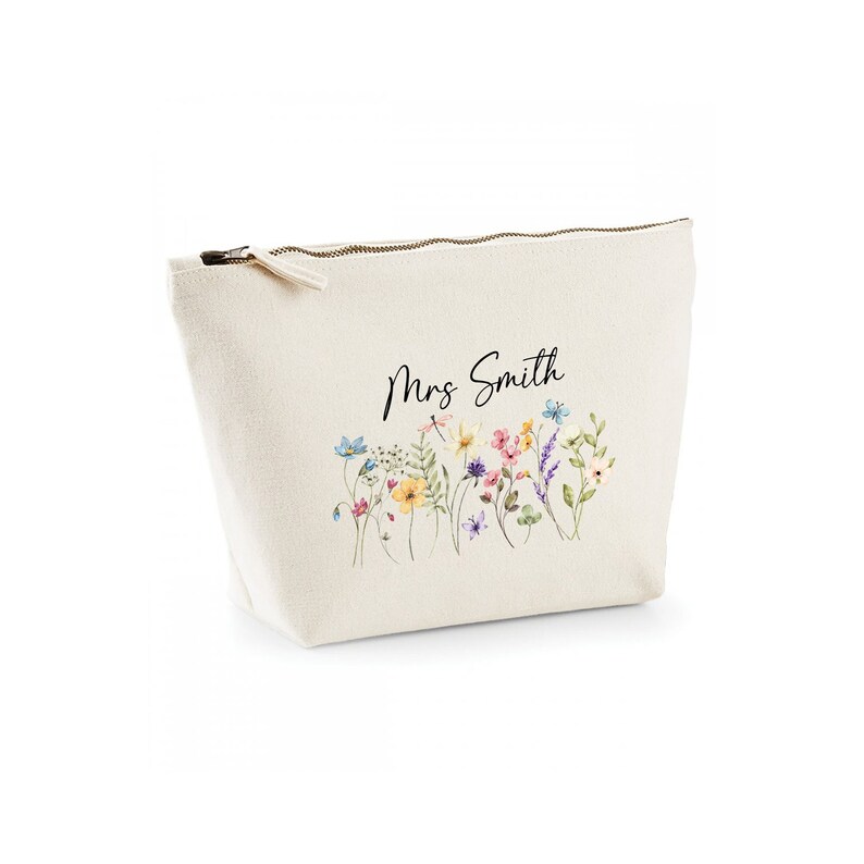 May include: A white canvas zippered pouch with a floral design and the text "Mrs. Smith" printed on it.