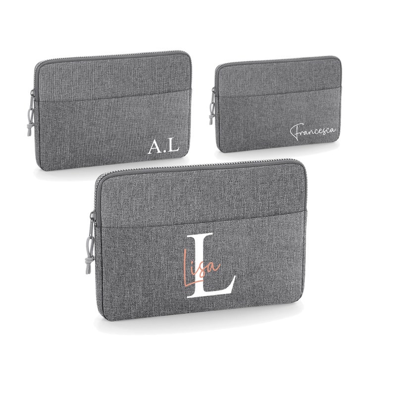 May include: Three gray laptop sleeves with zipper closures. The sleeves are personalized with the initials "A.L.", "Francesca", and a large "L" with the name "Lisa" written in a cursive font.