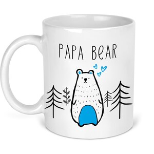 May include: White ceramic mug with a black and white illustration of a bear with blue accents. The text "Papa Bear" is printed in black on the mug.