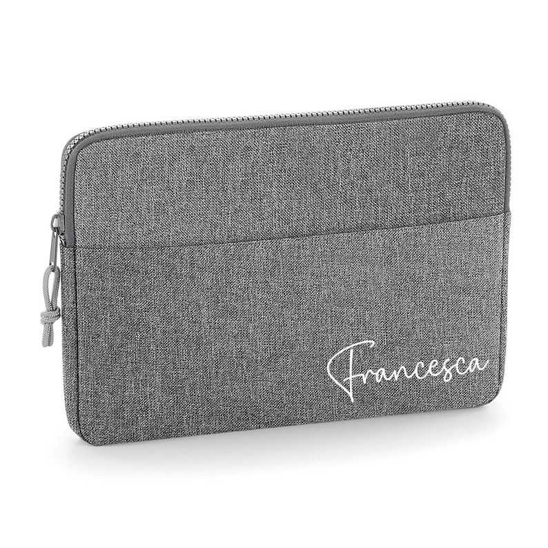 May include: Gray laptop sleeve with a zipper closure and a white embroidered name "Francesca".