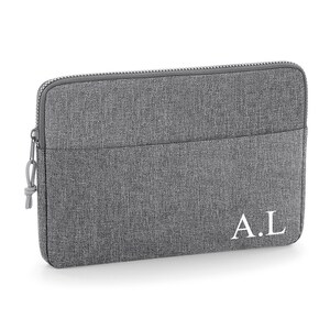 May include: Gray laptop sleeve with a zipper closure and a front pocket. The sleeve has the initials "A.L." embroidered in white on the front.