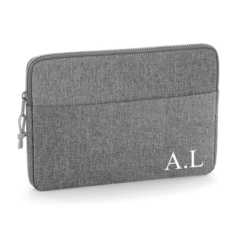 May include: Gray laptop sleeve with a zipper closure and a front pocket. The sleeve has the initials "A.L." embroidered in white on the front.